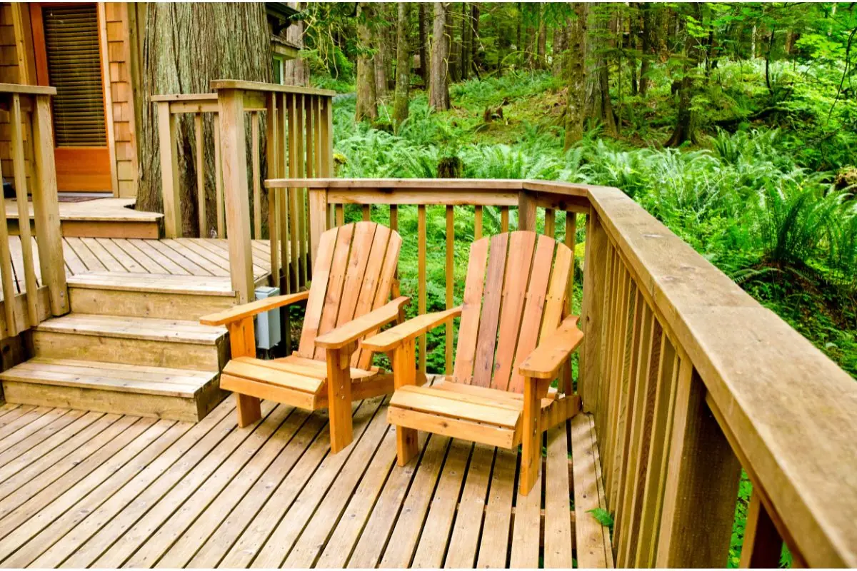 Two wooden chairs on a beautifully crafted deck surrounded by lush greenery – Discover how to create your perfect outdoor deck today!