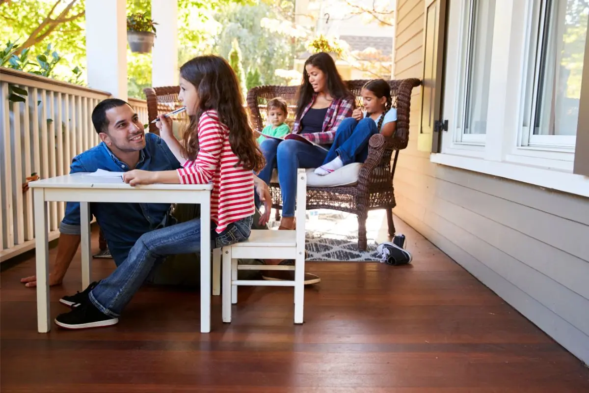 family sit on porch of house