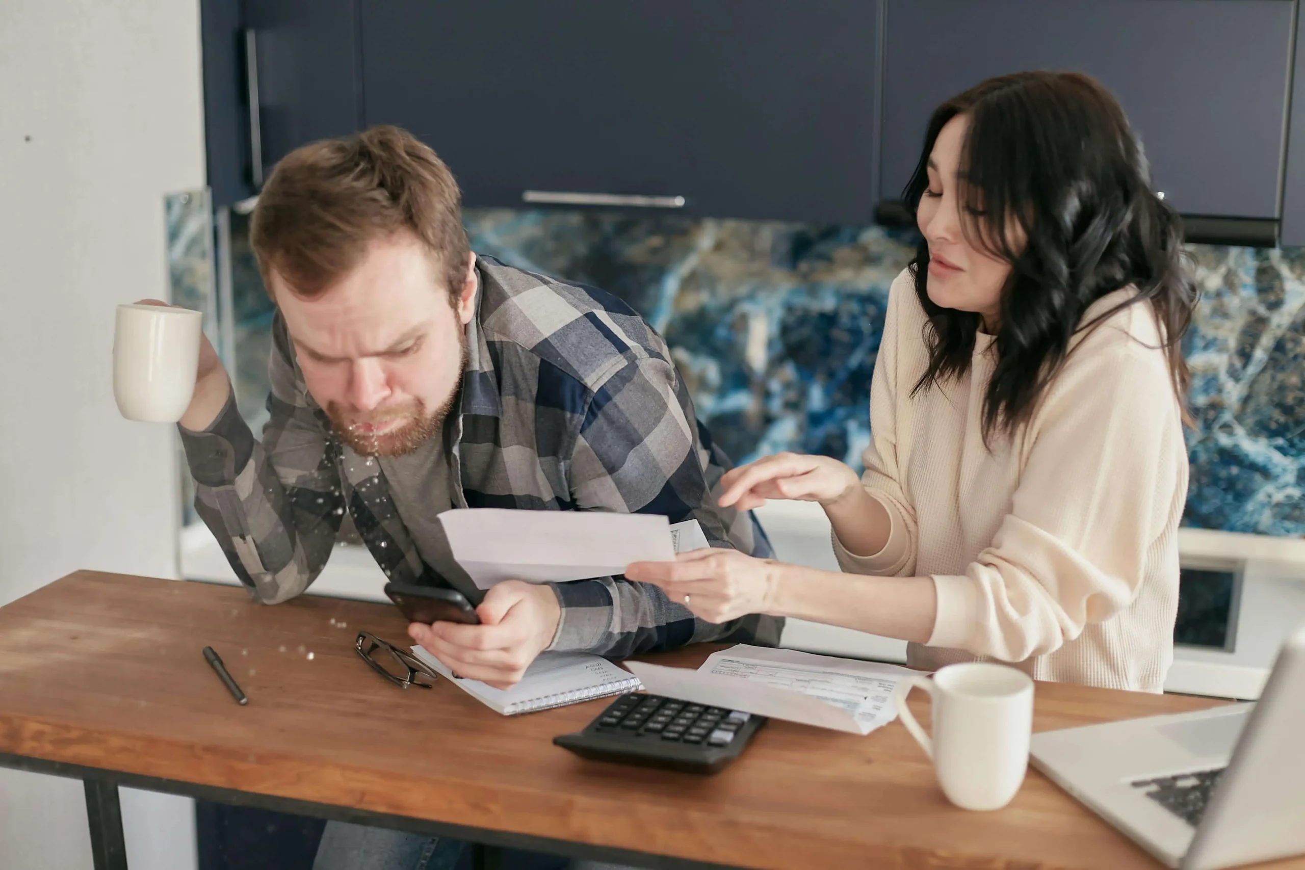 A couple looking stressed while reviewing bills and calculating costs, trying to estimate a deck project budget. Get help estimating your deck costs with expert advice today!