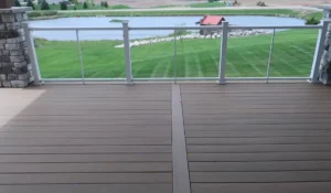 Stylish deck with glass railing overlooking a scenic lake. Elevate your outdoor living space—hire a professional contractor for your deck installation.