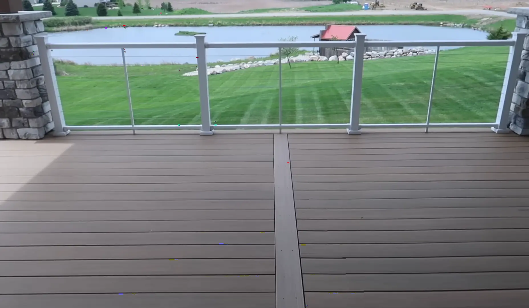 Stylish deck with glass railing overlooking a scenic lake. Elevate your outdoor living space—hire a professional contractor for your deck installation.